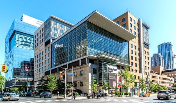 Hospital building on an intersection during a sunny day with blue skies.
