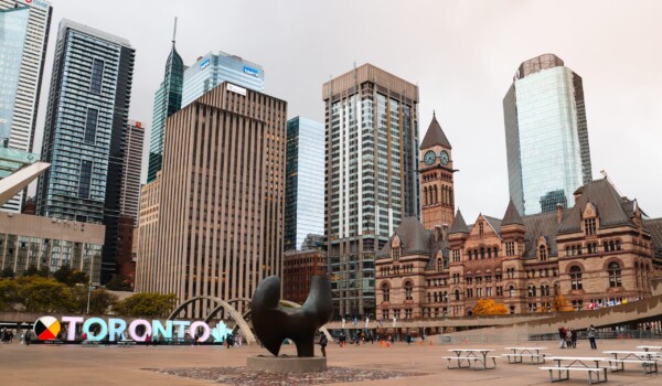 A sign with colourful letters and tall buildings outdoors